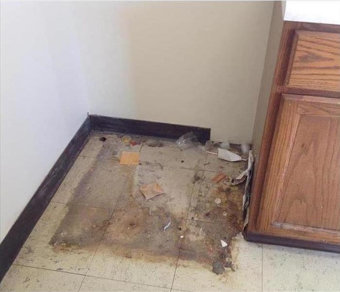Dirty floor underneath refrigerator.