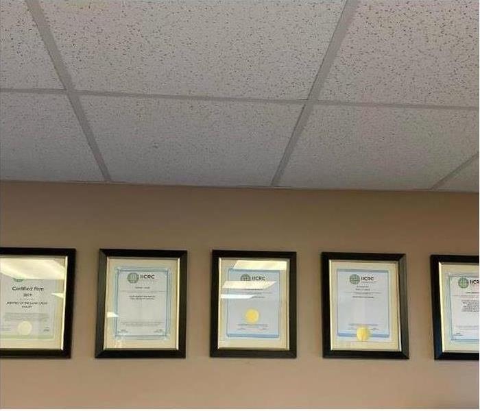 A wall with certifications hanging from it.