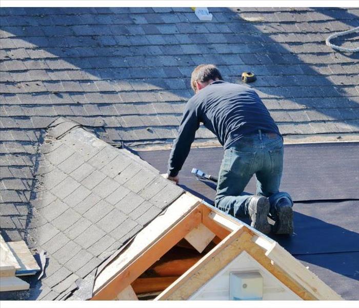 Man installing tarp on a roof